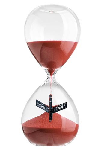 An hourglass with sand falling to the bottom, pilling on top of the Wall St. sign.