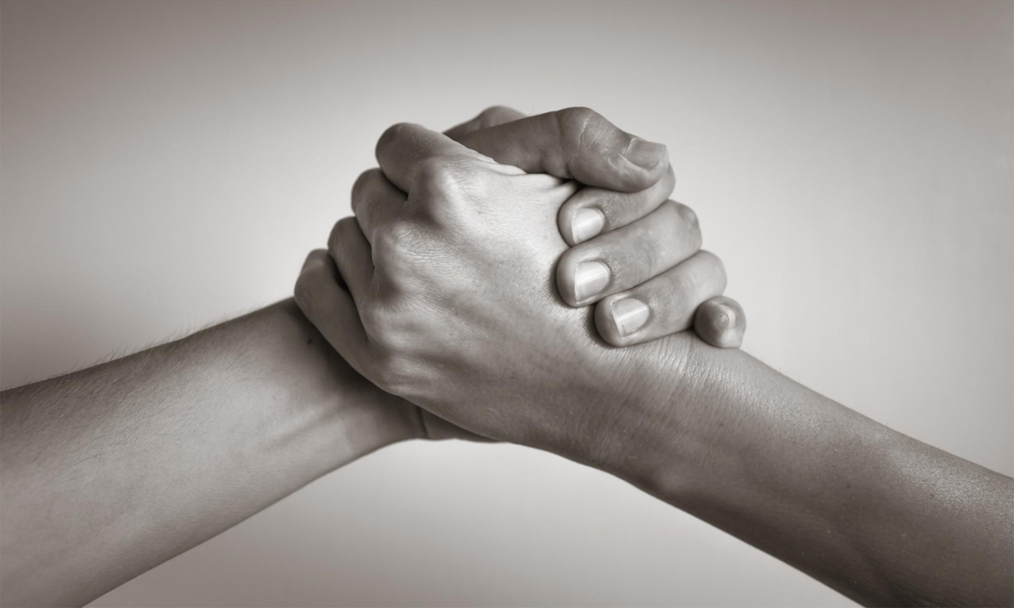 A close-up of the hands of two people giving each other a handshake of support.
